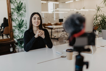 Young woman vlogger while recording her daily video blog. Vlogger using a camera mounted on a tripod to record her video.