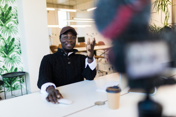 Young confident african man speaker talking on digital camera recording vlog. African male vlogger...