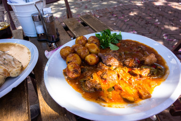 Table with lamb meat in vegetable sauce and potato.