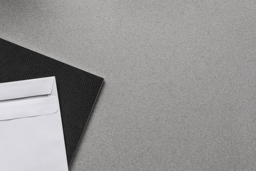 gray office desk top view with black notebook, envelope, white paper with space for text, banner concept, mockup background