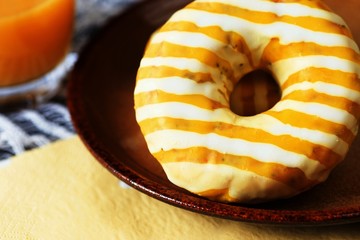 White-yellow striped donut on plate,juice.