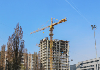 Fototapeta premium Crane builds a tall house against the blue sky