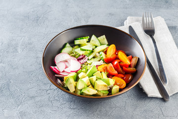 Vegan buddha bowl. Healthy vegetarian salad with cherry tomatoes, cucumber, radish,, avocado and lettuce.