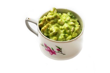 Avocado spread in cup on white.