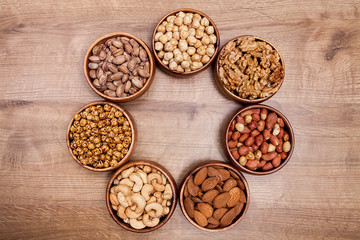 Different mixed nuts in a  bowls on wooden table. Healthy food and snack.