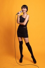Full body of beautiful young asian woman singer sing with microphone