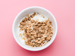Whole grains on yogurt in white bowl, pink background.