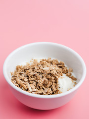 Whole grains on yogurt in white bowl, pink background.