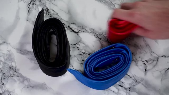 Caucasian man picking a neck tie from a marble counter and chooses the red one