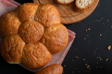 freshly baked  soft sweet divided bun with sesame seeds on it, torn off piece of breads
