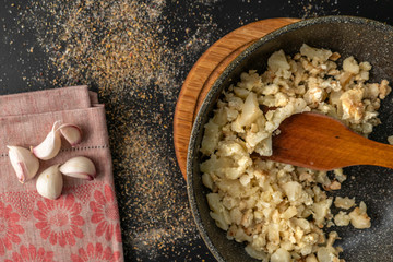fried or rosted cauliflower in a frying pan on a wooden cut board, vegeterian breakfasts