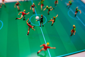 Side view of miniature toys figurines football (soccer) players on a computer pad.