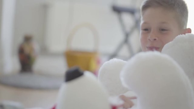 Close up portrait twin boy and girl sitting on the floor in living room and dont know how to share between them a big taddy bear. Kids pulling toy to each other to own it