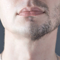 A man's half-shaved chin. White young man shaving.