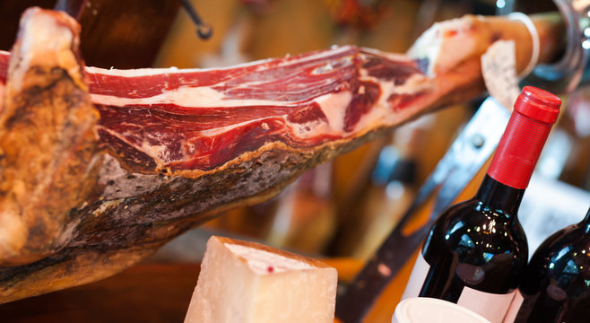 Still life of spanish pork jammon on holder, bottles of wine cheese and olives