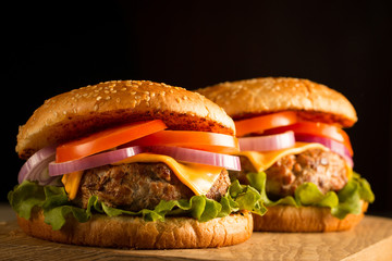 Home made hamburger with beef, onion, tomato, lettuce and cheese. Fresh burger close up on wooden rustic table with potato fries, beer and chips. Cheeseburger.