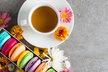 Still life and food photo of cake macarons in a gift box with flowers, a cup of tea on light background. Sweets and desserts concept of macaroons.