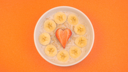 Ceramic bowl with oatmeal porridge with bananas and strawberry