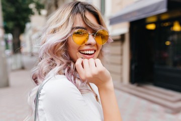 Close-up portrait of attractive joyful girl with amazing smile wears stylish yellow sunglasses and...