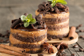 Dark chocolate cakes on black slattern board with mint, cinnamon, coffee beans on a wooden  background. Tasty dessert food concept.