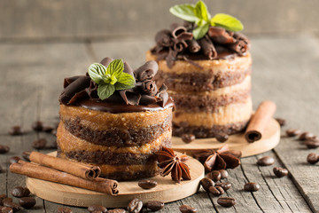 Dark chocolate cakes on black slattern board with mint, cinnamon, coffee beans on a wooden  background. Tasty dessert food concept.