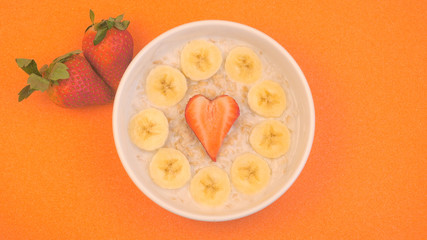 Ceramic bowl with oatmeal porridge with bananas and strawberry