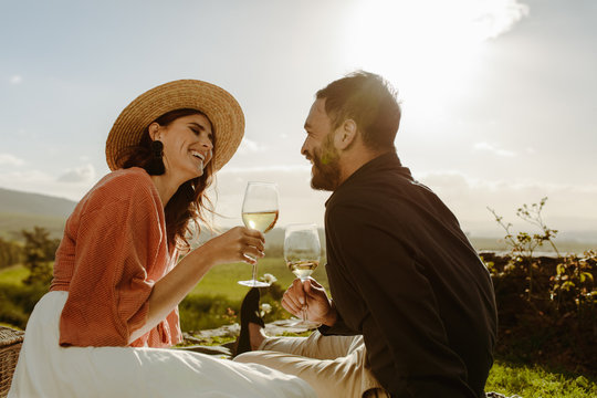 Couple sitting near a vineyard on a date drinking wine