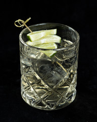 transparent cocktail with lime in a glass on a black background