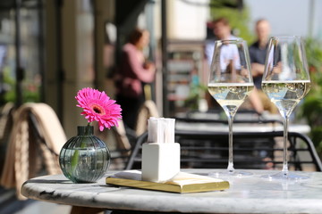 Street cafe, table set in a restaurant outdoor, romantic meal, elegant setting for celebration and date. Two glasses of champagne, napkins and flower on a table