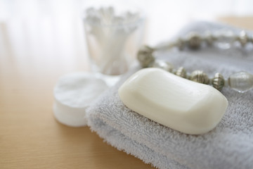 Obraz na płótnie Canvas Weiße Seife auf Handtuch mit Wattepads und Kette