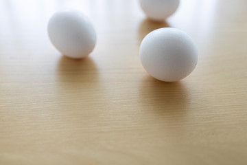Rohe Eier auf Tisch aus Ahorn vor Fenster mit Gardine