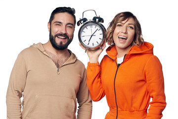 Happy young couple in home clothes holding big alarm clock