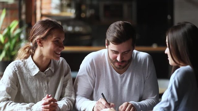 Happy young couple clients sign insurance contract handshake broker