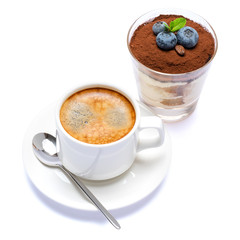 Classic tiramisu dessert with blueberries in a glass and cup of coffee isolated on a white background with clipping path
