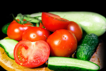 Tomatoes, cucumbers, and zucchini on a wooden board, close-up
