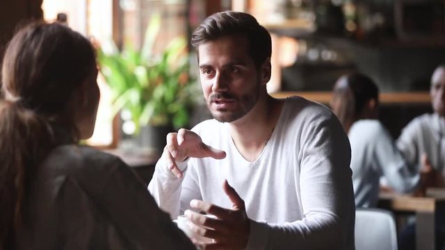 Young man having conversation with woman sit at cafe table
