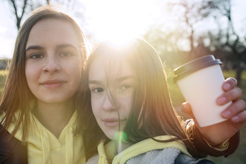 Two happy teenage friends taking selfie with mobile phone while walking in the park