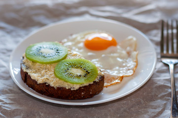 Delicious and healthy breakfast. Scrambled eggs and kiwi sandwich on a white plate, close-up, top view and side view