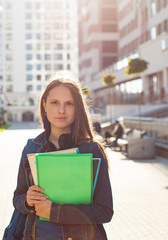 Back to school student teenager girl holding books and note books wearing backpack. Outdoor portrait of young teenager brunette girl with long hair. girl on city