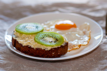 Delicious and healthy breakfast. Scrambled eggs and kiwi sandwich on a white plate, close-up, top view and side view