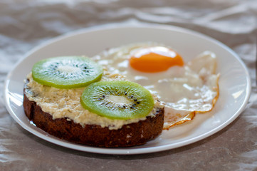 Delicious and healthy breakfast. Scrambled eggs and kiwi sandwich on a white plate, close-up, top view and side view