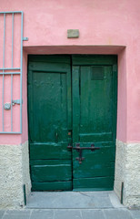 Close-up of an old green door on a pink exterior wall background, Vernazza, Cinque Terre, Liguria, Italy 