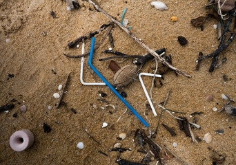 Plastic straws garbage left on the sand. Close up.