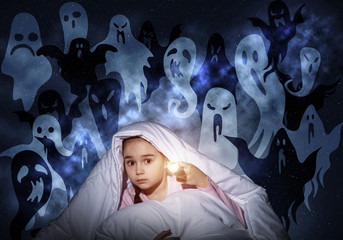Scared girl with flashlight under blanket