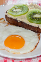 Healthy, tasty breakfast, quince juice, whole-grain kiwi sandwich and fried egg on a white plate