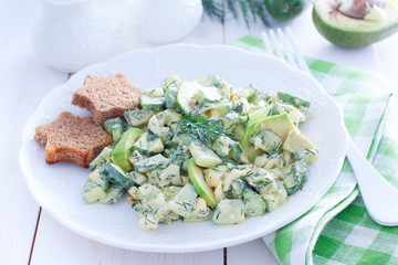 Salad with cucumbers, egg and avocado on a white plate, horizontal