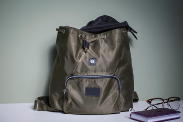 Stylish backpack of protective color from waterproof fabric on a white table.