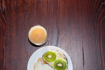 Healthy, tasty breakfast, juice, wholemeal bread sandwich with kiwi and a fried egg on a white plate, flat lay