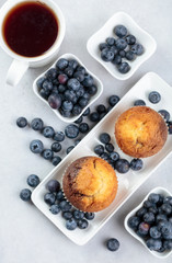 Muffins and blueberries on a white kitchen table.
