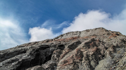 Huge stone mountain on a blue sky with a bit of cloud.